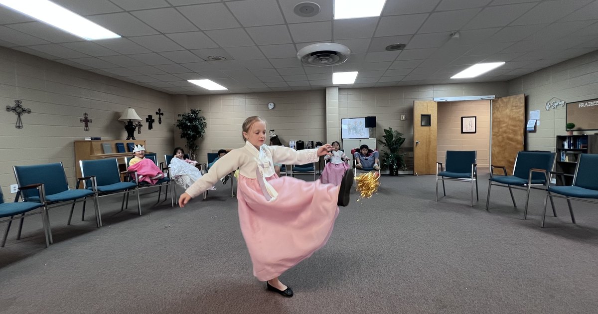 A student in hanbok kicking a jegi into the air at the Cheonan rest stop.