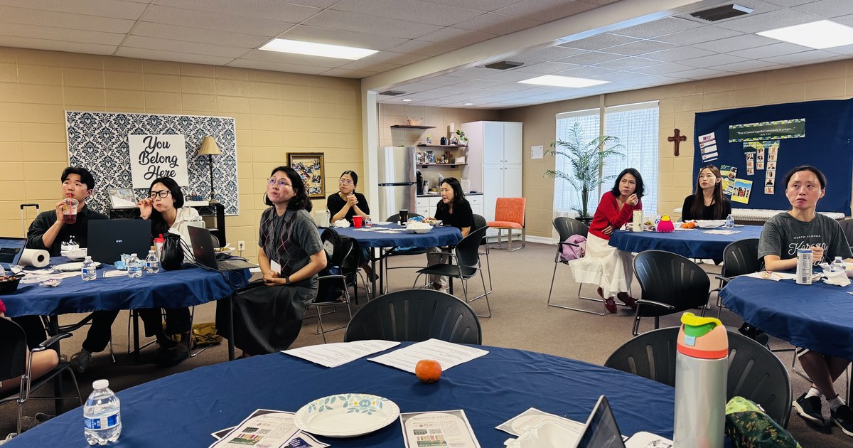 Teachers of the North Alabama Korean School seated at tables, watching a presentation at the fall teacher demonstration day.